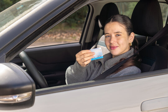 New driver showing her driving license through car window