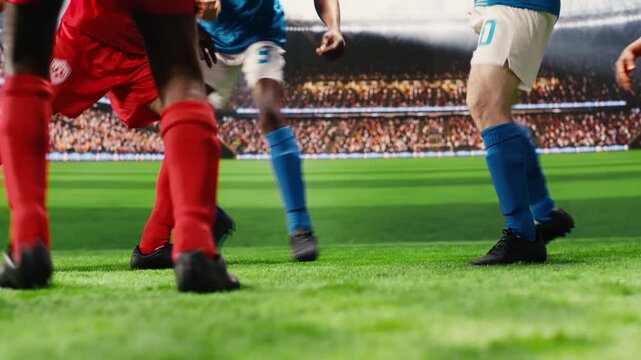 Lower body scene with soccer players in red and blue uniforms dribbling each other for ball possession, running across pitch during match play.