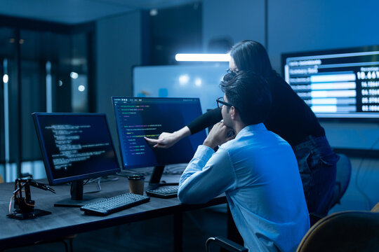Asian happy woman and man programmer team coding software at computer in dark tech office, Concept of digital transformation, modern cyber security, startup teamwork and future IT digital network