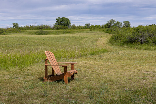 Wooden Adirondack Chair in a Peaceful Sand Greens Rural Golf Course Under Cloudy Sky.