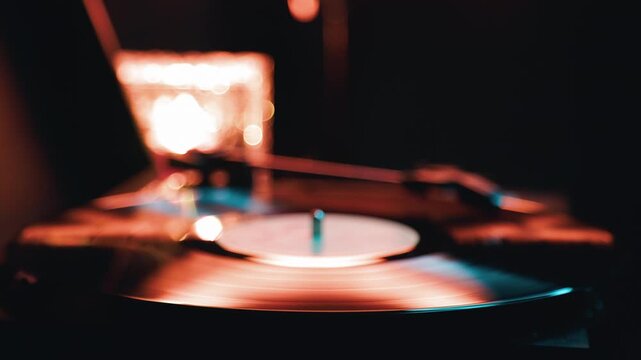 Vinyl record spinning on a classic turntable. Analog music playback equipment with warm vintage lighting. Retro audio device detail for high fidelity sound lover.