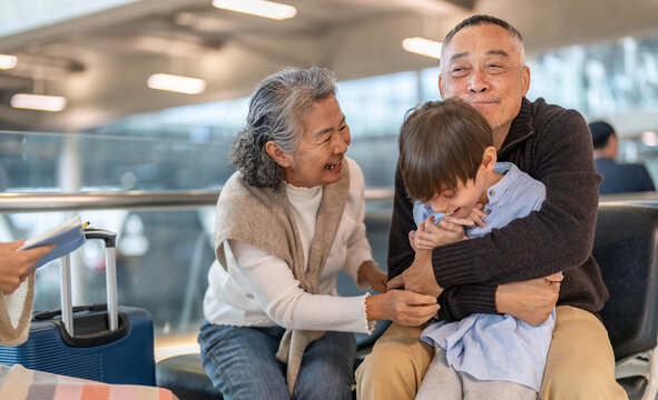 Asian multigenerational family at airport traveling with kids and grandparents, joyful moments of vacation, family holiday trip with luggage before flight, tour, friendly airline, hotel for families