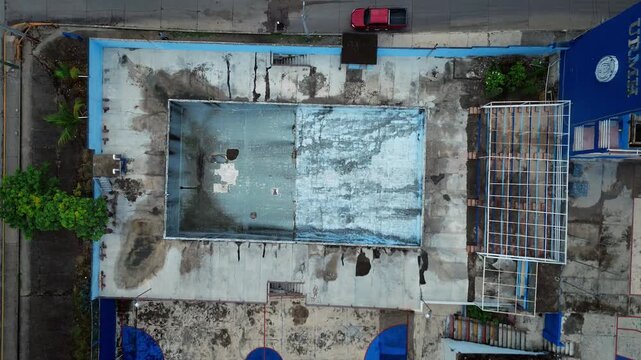 Drone aerial documentation of abandoned blue school structure with vacant pool showing deterioration and abandonment in Ciudad Madero
