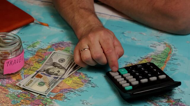 Planning a budget trip with a calculator and cash for savings and expenses