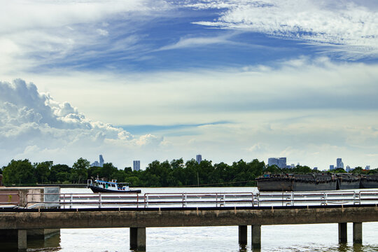 River landscape with bridge boat skyline cloudy sky water tree city horizon daylight