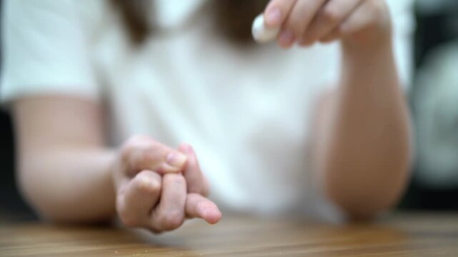 Woman carefully pricks her finger with a white lancet to collect a blood sample for medical analysis and health testing.