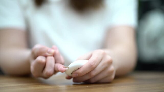 Woman carefully pricks her finger to collect a blood sample for medical analysis and laboratory testing.