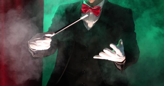 Magician showing trick with wand on stage with smoke, closeup
