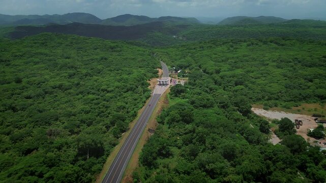 Drone forward approach of Rio Verde Ciudad Valles highway showing toll booth and dense tropical mountain forest landscape