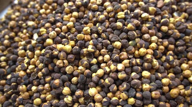 A close up view of delicious roasted split brown chickpeas piled up into a large mound for sale at a market