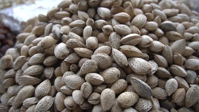 A huge large mountain of raw organic almonds in their hard shells displayed for sale at a traditional market
