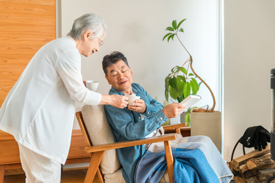 A senior couple relaxing in the living room while drinking coffee.