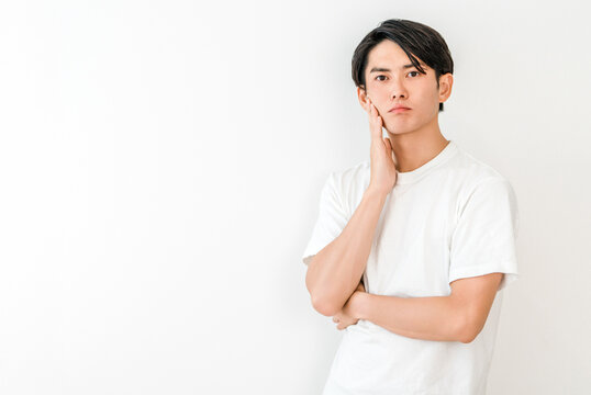 A young Asian man resting his chin on his hand (dissatisfied, worried, troubled, troubled, anxious, imagining)