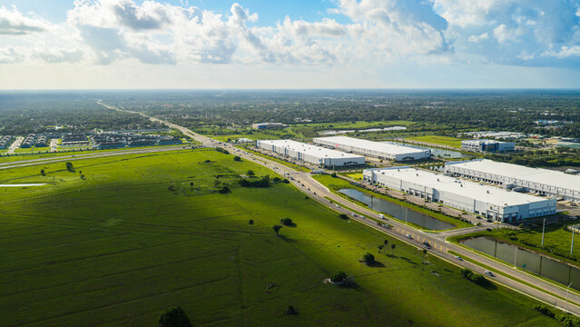 Urban sprawl casts a dark shadow over pastoral land. Massive warehouses, busy highways, and new housing developments border a large cattle pasture in Bradenton, FL. (US 301 & 44th Ave E)