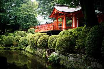Fototapeta premium Traditional Japanese Shrine Architecture by a Peaceful Garden Pond and Trees