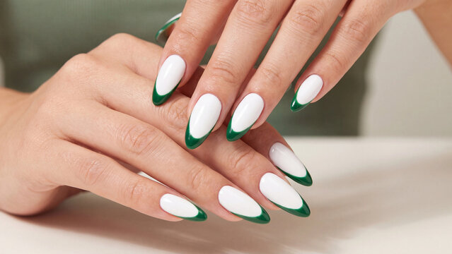 Fingernails painted with a classic white base and dark green tips create a timeless and sharp aesthetic that highlights the precision of a professional manicure on well-maintained hands.