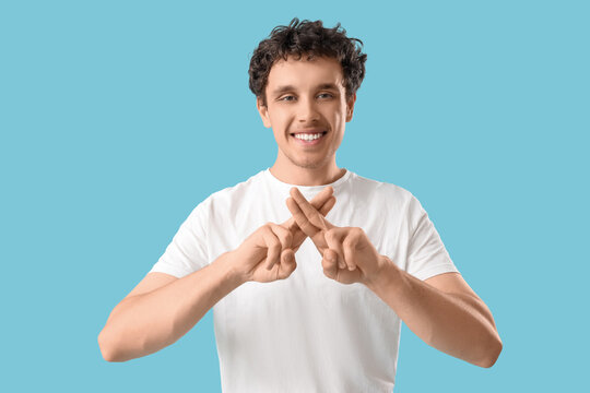 Young man using sign language on blue background
