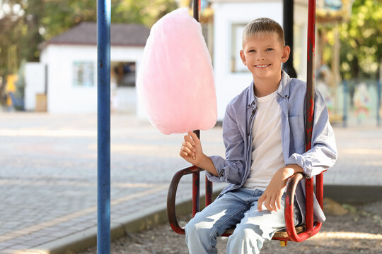 Teen boy with cotton candy on swing at playground