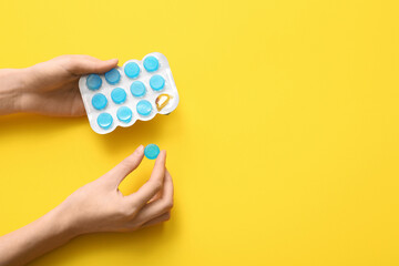 Obraz premium Female hands with cough drops in blister on yellow background