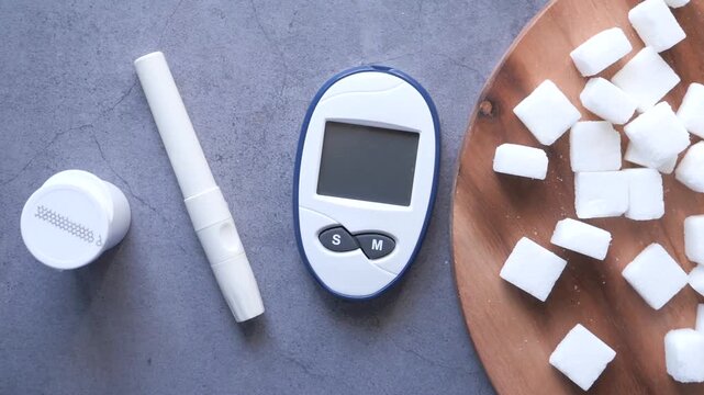 Close up on diabetes testing kit with sugar cubes, representing blood sugar control