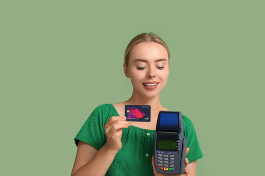 Pretty young woman with credit card and payment terminal on green background