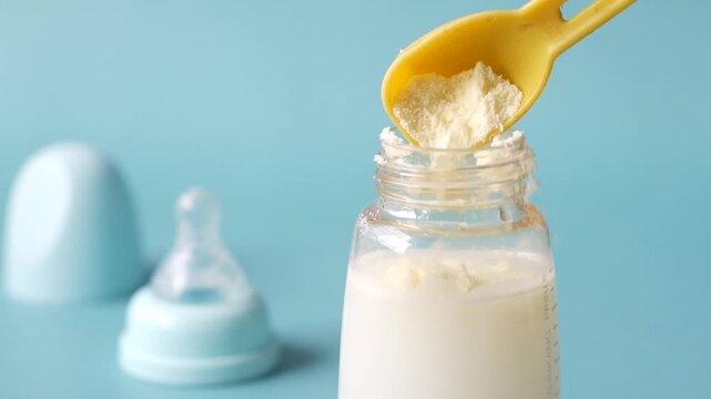 Adding powder formula to milk in baby bottle for infant nutrition preparation