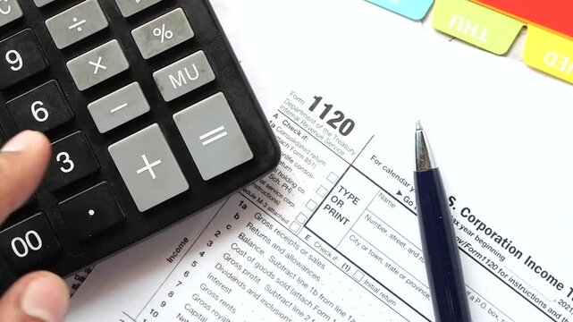 Calculating business taxes with a calculator and tax form for corporation income