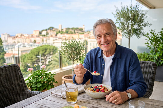Senior Man Enjoying Healthy Salad on Sunny Balcony with City View