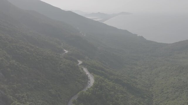 Freight and passenger trains travel through the breathtaking Hai Van Pass in Hue, Vietnam, winding along dramatic coastal mountains. Scenic railway transportation with tunnels, lush forests, and panor