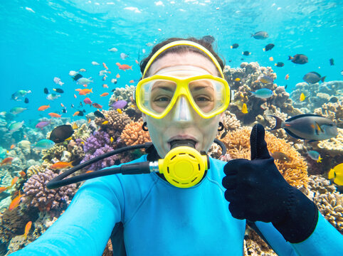 Scuba Diver Woman Giving Thumbs Up Gesture Near Diverse Coral Reef and Tropical Fish, Adventure Tourism Underwater Activity