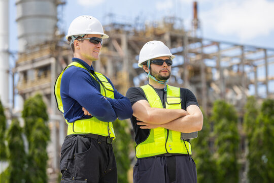 Industrial engineers team standing with arms crossed at oil refinery plant, Worker and technician team in safety gear observing operations at industrial site