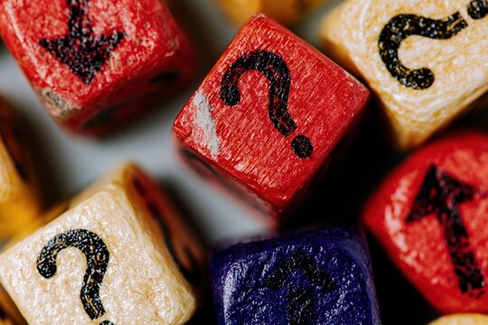 Colorful wooden cubes with question marks and arrows symbols in a cluttered overhead flat-lay for decision making and direction concepts