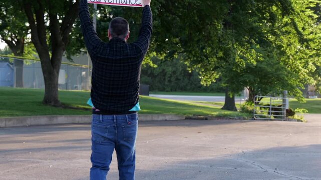 Demonstrator holding a Citizens Over Surveillance sign, protesting mass tracking, license plate readers, Fourth Amendment overreach illegal search