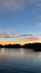 Obraz premium Tranquil Lake Landscape at Sunset with Tree Silhouettes and Water Reflection