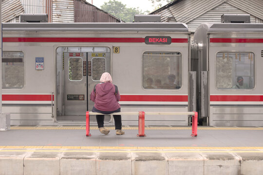 Woman waiting on bench for commuter train to Bekasi