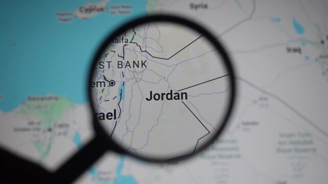 Magnifying glass highlights Jordan on a Middle East map amid Iran war tensions involving Israel and USA, showing regional conflict, borders, security risks, geopolitical instability and crisis concern