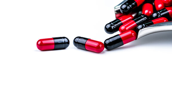 Red and black capsule pills on stainless steel drug tray. Antibiotics drug resistance. Global healthcare. Antimicrobial capsule pills. Pharmacy background. Health budgets and policy. Pharmaceutical.