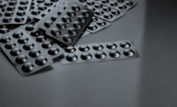 Silver aluminum blister packs with copy space on gray background for pharmaceutical industry. Hospital medicine supplies, pharmacy products, prescription drug packaging and healthcare retail market.