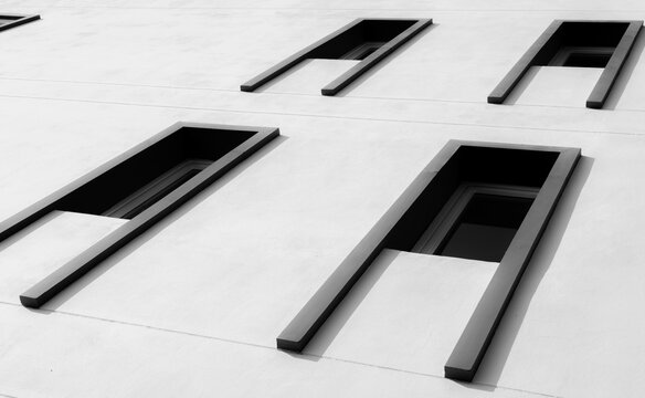 Looking up view of exterior modern building with glass window abstract. Real estate and corporate construction. Exterior architecture design. White concrete wall and glass window with unique design.