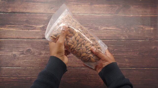 Hands opening a bag of almonds in a kitchen