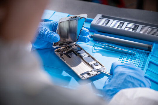 Smartphone technician repairing disassembled mobile phone hardware.