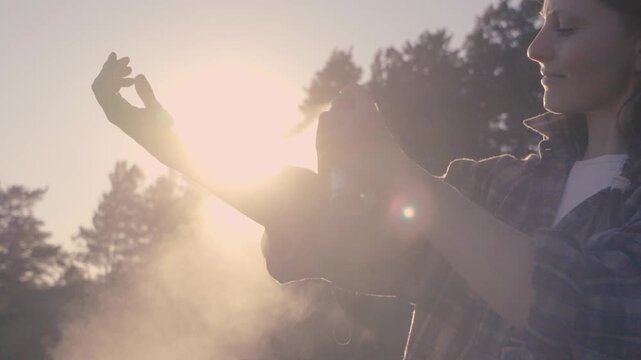 Woman Applying Insect Repellent on Arms Before Hiking Running Walking or Outdoor Recreation at Sunset