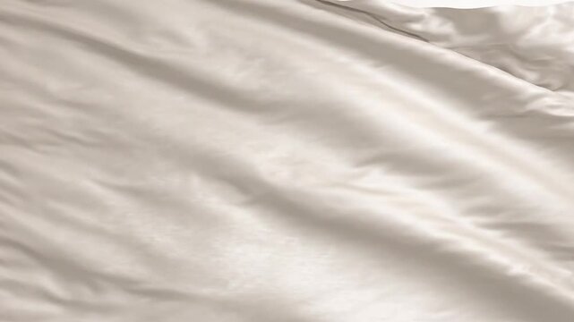 Soft beige wrinkled fabric texture background of a folded cotton bed sheet with gentle waves and shadows