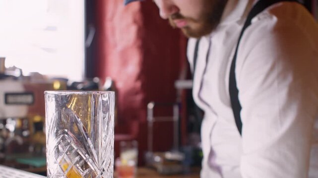 Cold drink. Barista working. Male barman serving cocktail in glass decorating with lemon spiral zest scooping ice cubes mixing in professional pub.