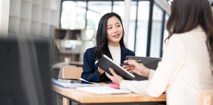Professional Asian businesswoman talking and consulting with colleague during office meeting