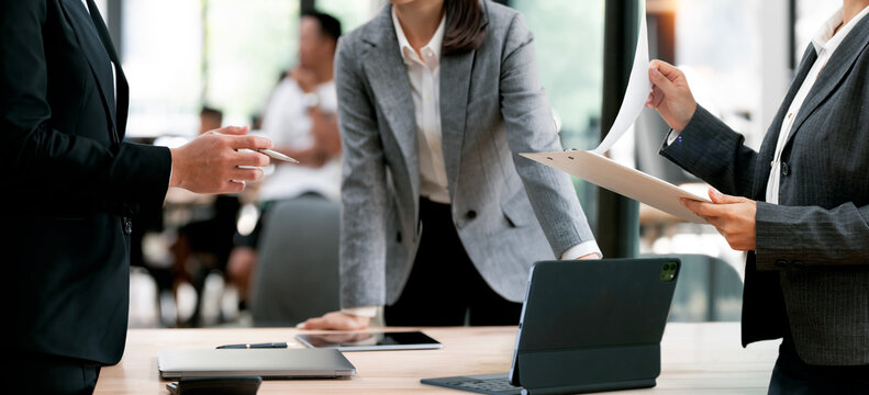 Business people discussing project and reviewing documents on clipboard during a team meeting in office