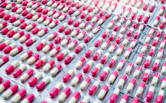 Closeup pink-white antibiotic capsule pills in blister pack. Antimicrobial drug resistance. Pharmaceutical industry. Global healthcare. Pharmacy background. Pharmaceutical product. Amoxicillin capsule