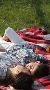 Woman lying on a blanket posing and relaxing, in grass field with red and white patterned blanket, with blanket, grass, from a top-down perspective perspective, with green, red accents.