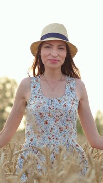 a woman is seen walking through a vast open field of tall grass or wheat, exuding a relaxed and serene atmosphere, with her attire featuring blue and white hues, captured from an eye-levelv.