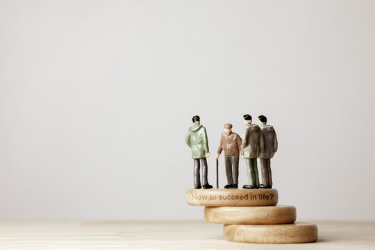 Miniature people with senior man on wooden steps stamped with How to succeed in life text. Concept of mentorship, career guidance, life coaching, and wisdom transfer.
